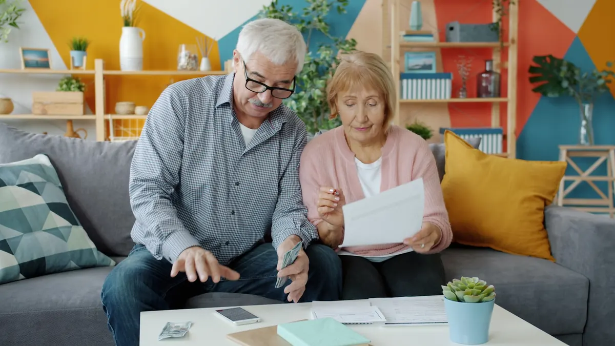 Couple de seniors examinant ses dépenses de santé et sa cotisation de mutuelle à la maison